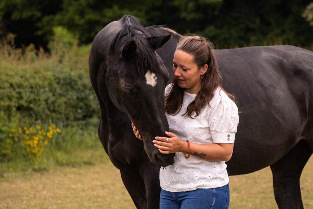 Vrouw knuffelt zwart paard